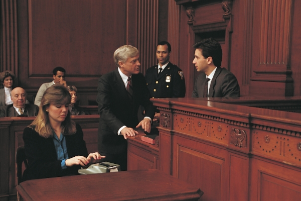 A lawyer approaching his witness on the stand during a trial.