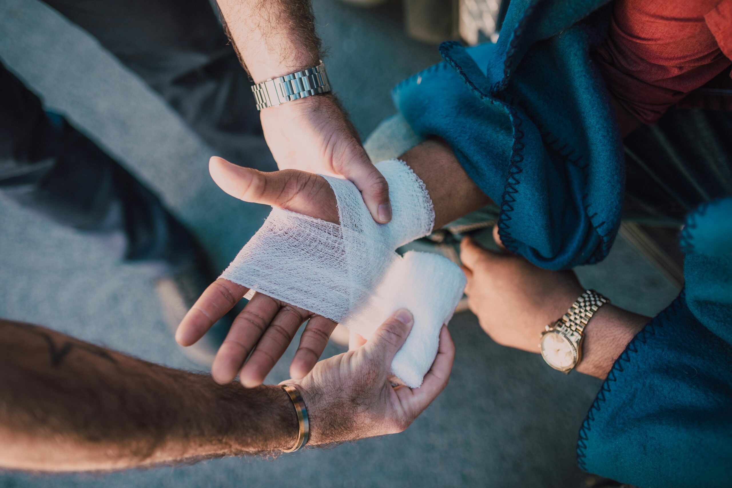 a first responder wrapping a bandage around the personal injury victim's hand