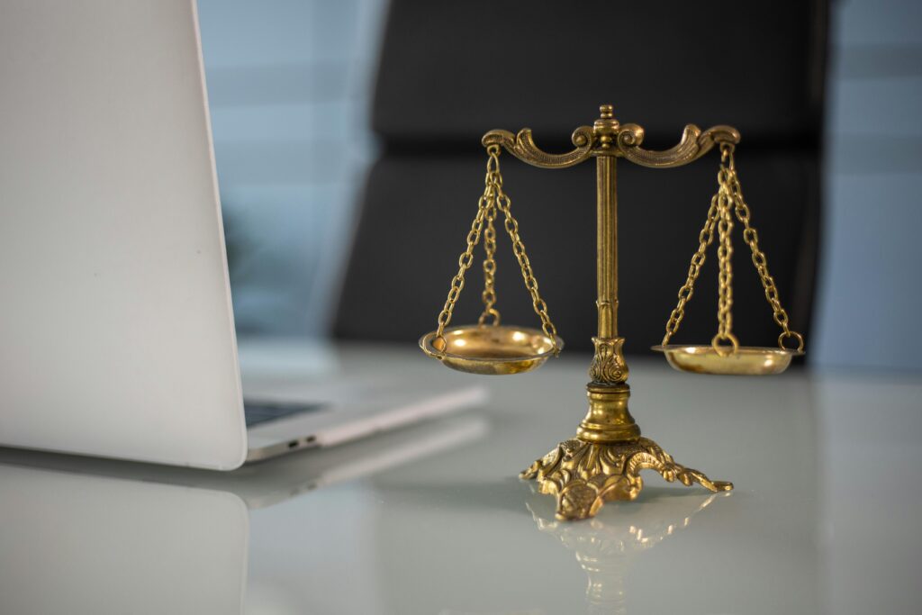 a scale of justice sitting next to a laptop on a desk at a personal injury law firm 